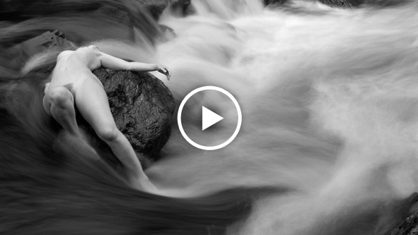 nude art model on rocks in a river